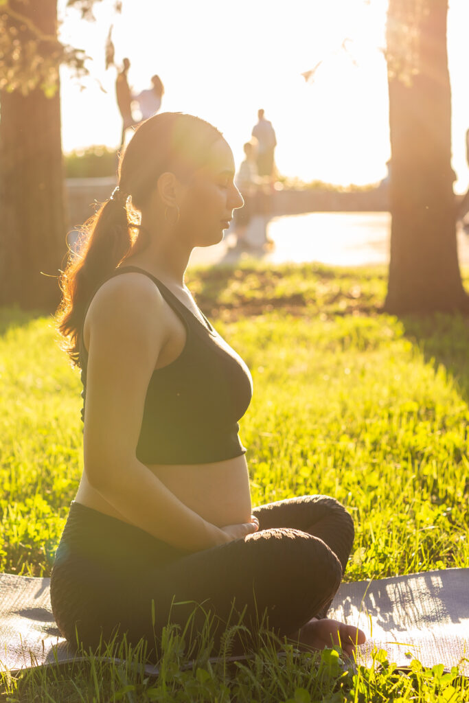 Schwangere Frau macht Rückbildungsübungen draußen auf einer Yogamatte