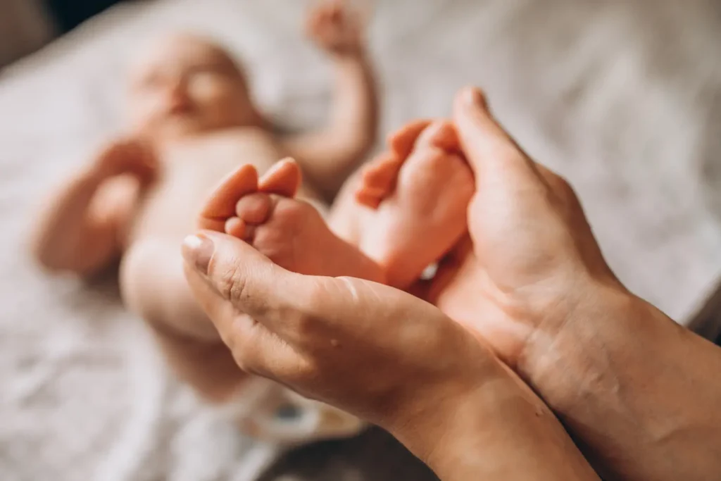 Mutter massiert Baby auf weicher Decke